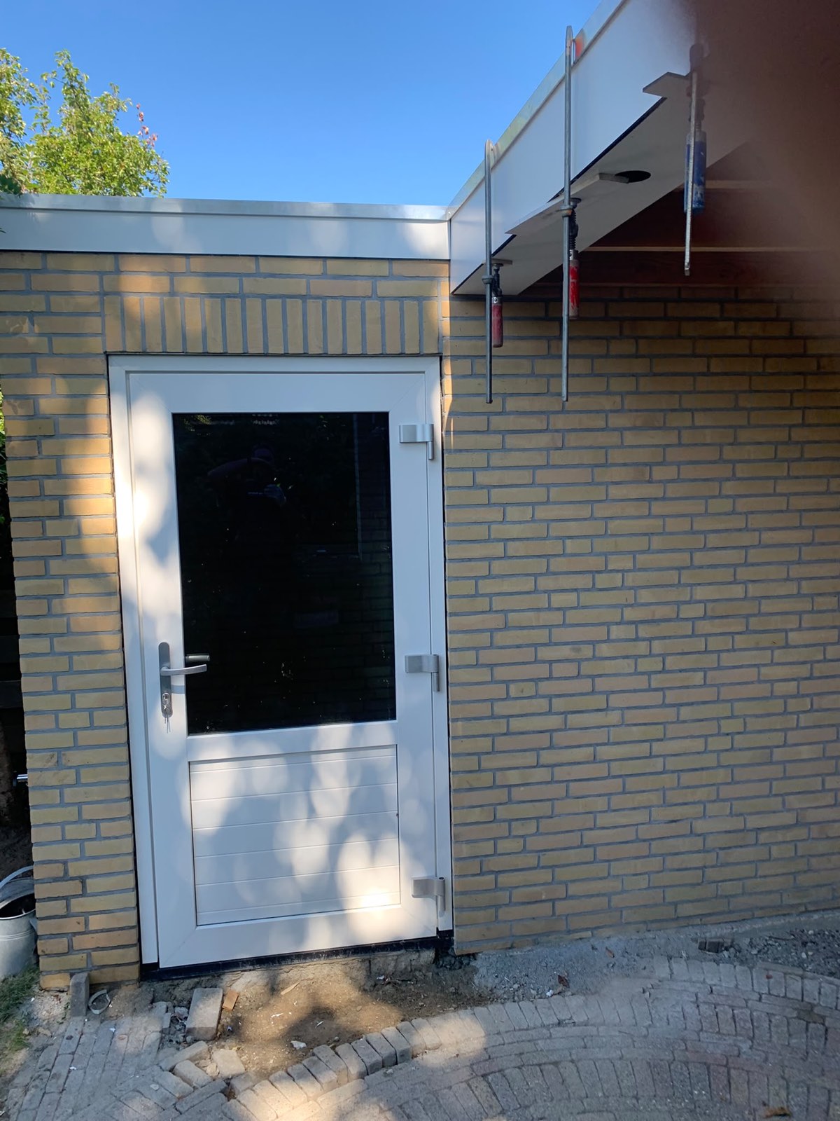 Gemetselde berging van gele baksteen met een witte deur